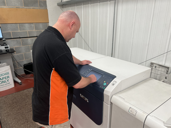 Team member Peter preparing printing machine prior to production of printed school prospectus.